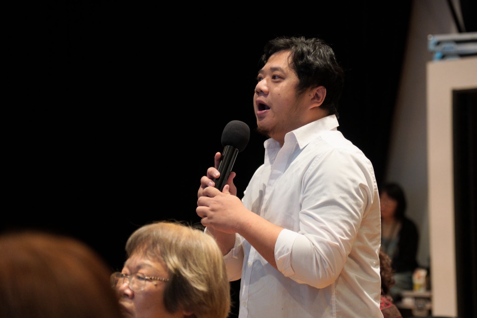 導演陳仕弦在珍珠講堂講座現場手持麥克風與講者交流